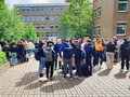 Zahlreiche Menschen stehen vor dem Studienort Münster und unterhalten sich.