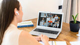 Eine Frau sitzt vor einem Laptop und nimmt an einem Online-Meeting teil.