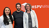 3 Persoen stehen vor der orangenen Fotowand der HSPV NRW und posieren für ein Foto.